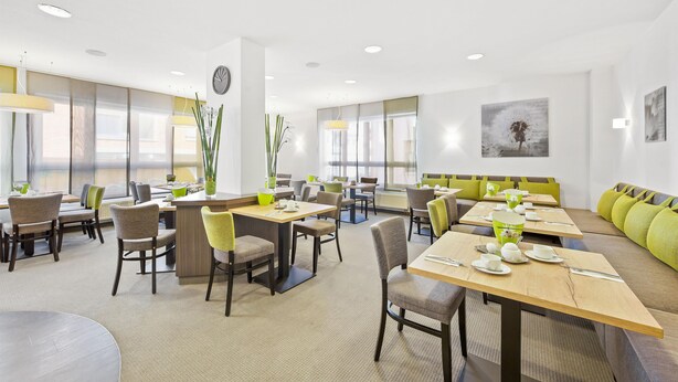A modern dining area with tables, chairs, and a seating area with cushions. - Best Western Hotel Favorit (Ludwigsburg)
