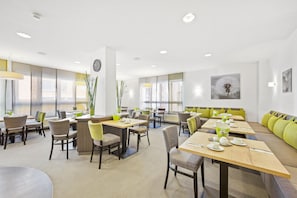 A modern dining area with tables, chairs, and a seating area with cushions. - Best Western Hotel Favorit (Ludwigsburg)