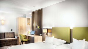 A hotel room with a large bed, a desk with a laptop, a sofa, and a chair. - Best Western Hotel Favorit (Ludwigsburg)