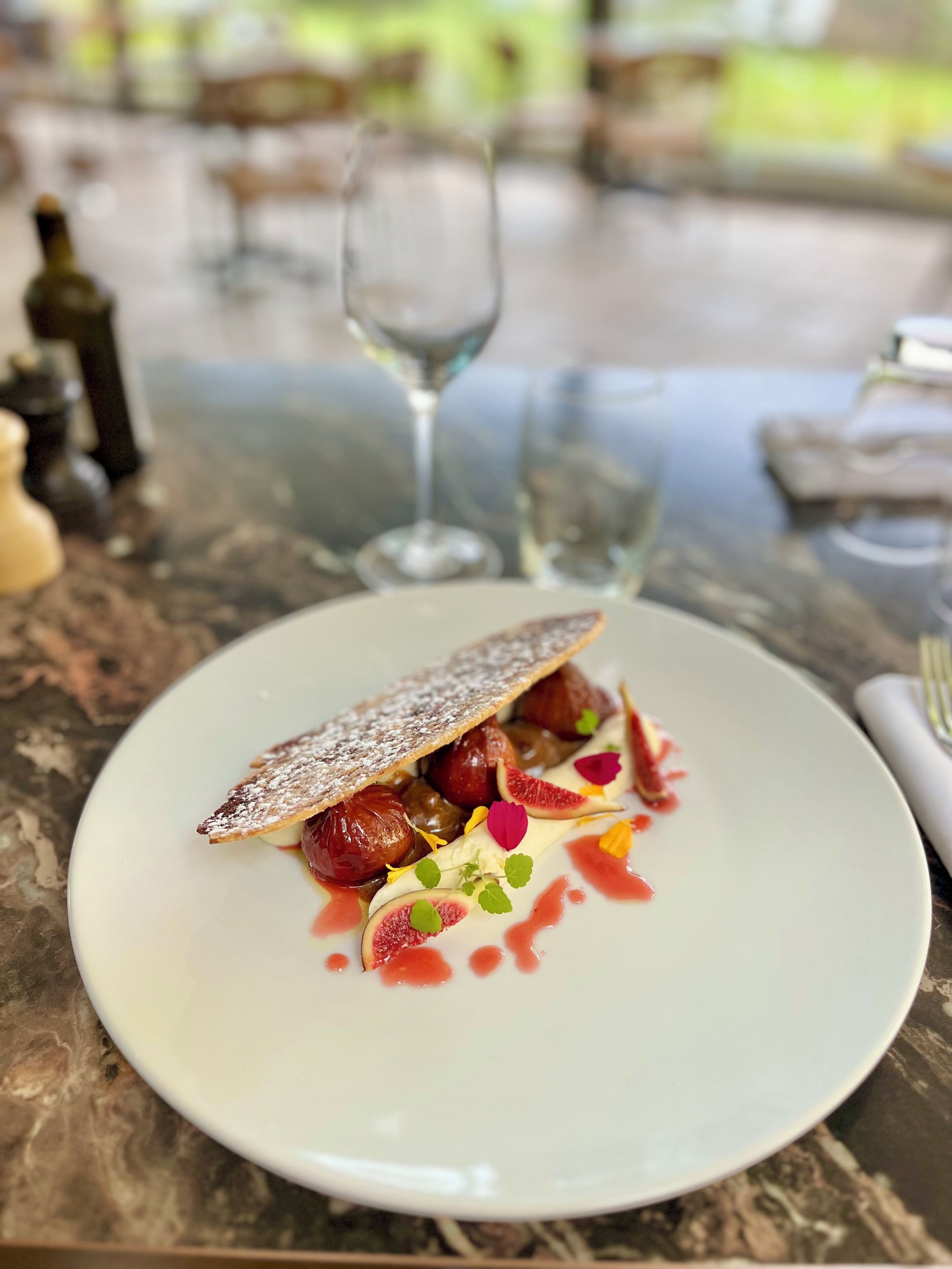 Un plato con un pastel, higos y salsa roja sobre una mesa de mármol.