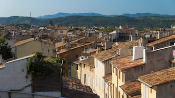 A densely packed urban area with traditional architecture, featuring closely built buildings with terracotta roofs and a mountainous backdrop.