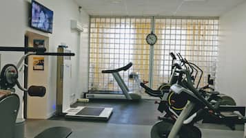 Un gimnasio con equipo de ejercicio, una cinta de correr y un reloj en la pared.