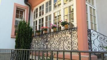 Un edificio con balcón, barandillas de hierro forjado y plantas en macetas.