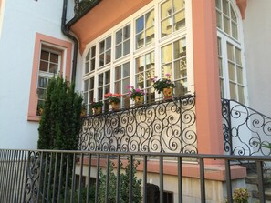 Um edifício com varanda, adornado com grades de ferro forjado e plantas em vasos.