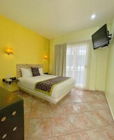 Una habitación de hotel con una cama, un escritorio, un teléfono y una televisión instalada en la pared.