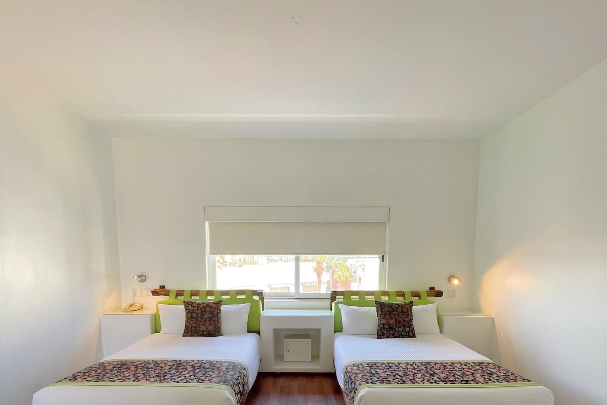 Une chambre avec deux lits simples, une petite fenêtre et un plancher en bois.