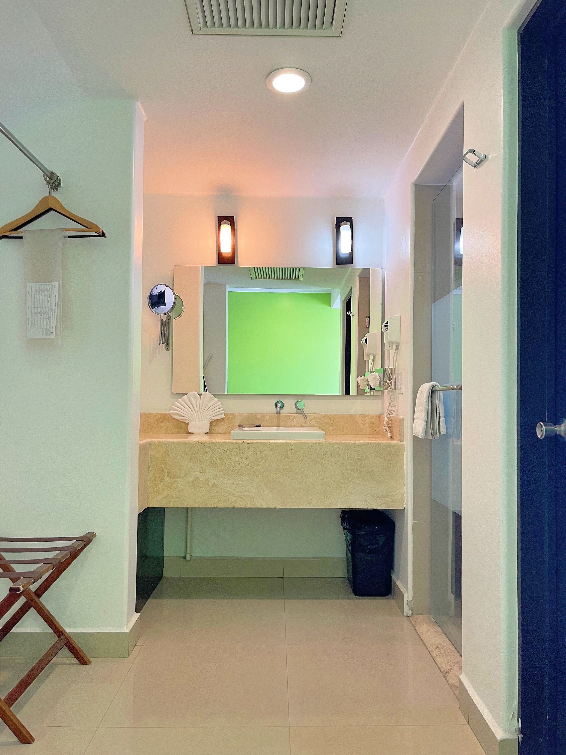 A bathroom with a sink, mirror, and a green screen.