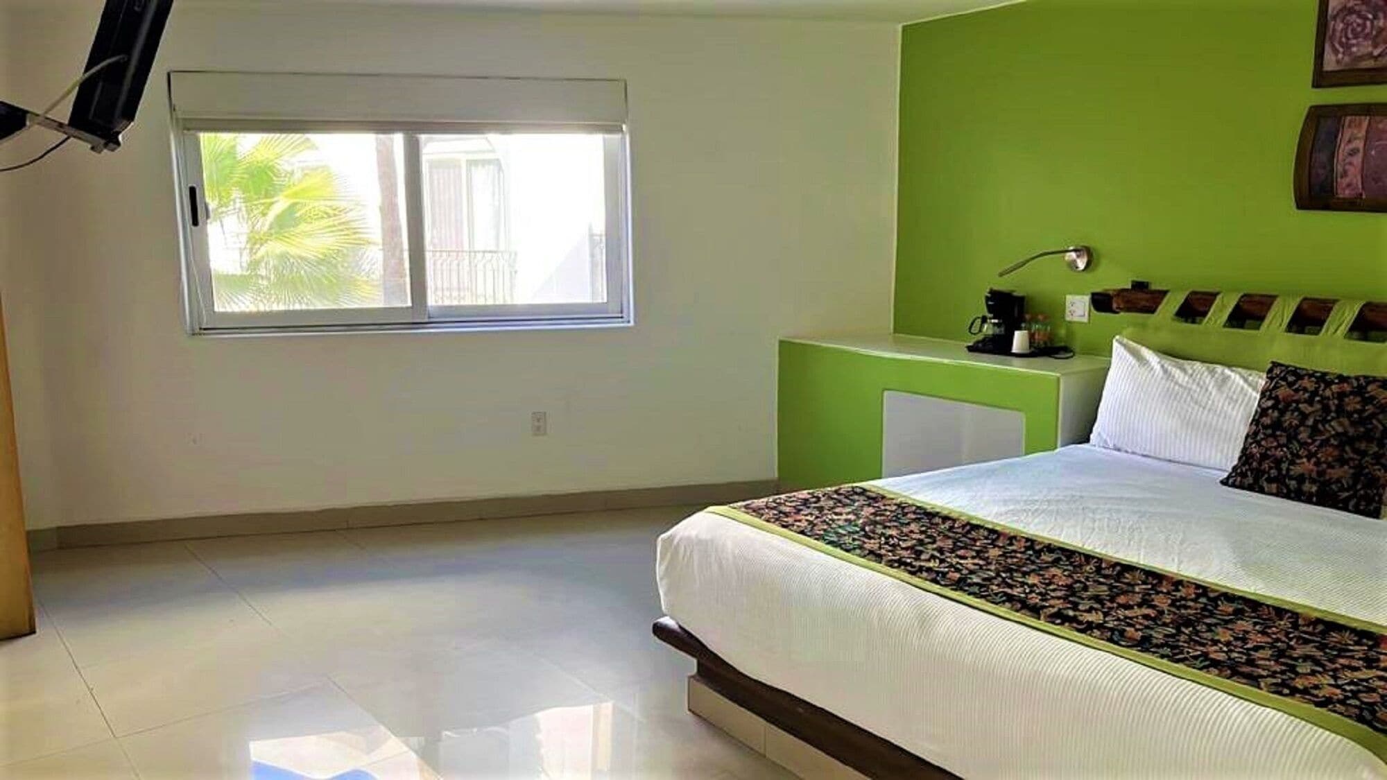 Une chambre à coucher avec un lit, une table de chevet, une fenêtre et un mur d’accent de couleur verte.