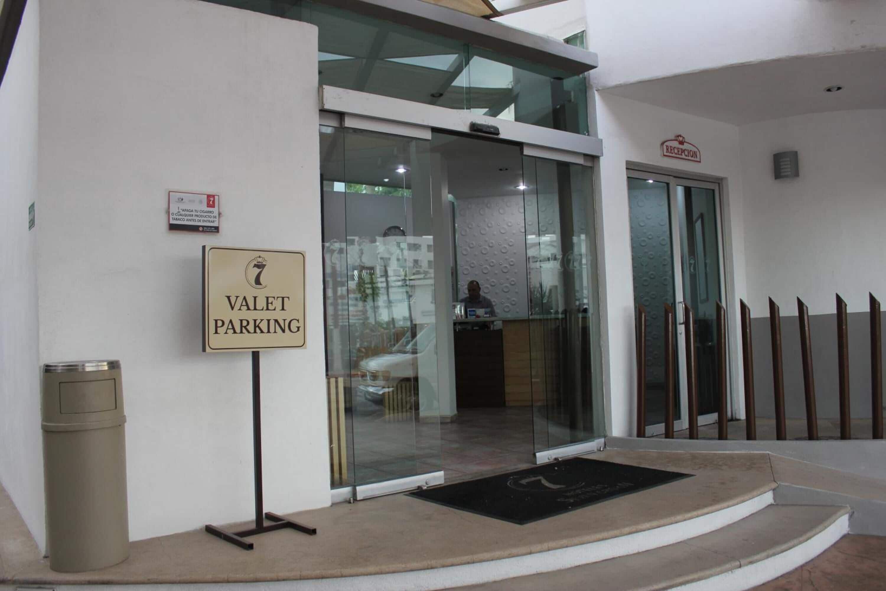 A hotel entrance with a valet parking sign, a reception area, and a glass door leading inside.