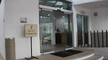A hotel entrance with a valet parking sign, a reception area, and a glass door leading inside.