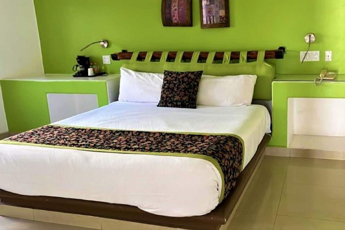 Un lit avec une couvre-lit blanche à motifs, une tête de lit et une table de chevet avec une lampe.