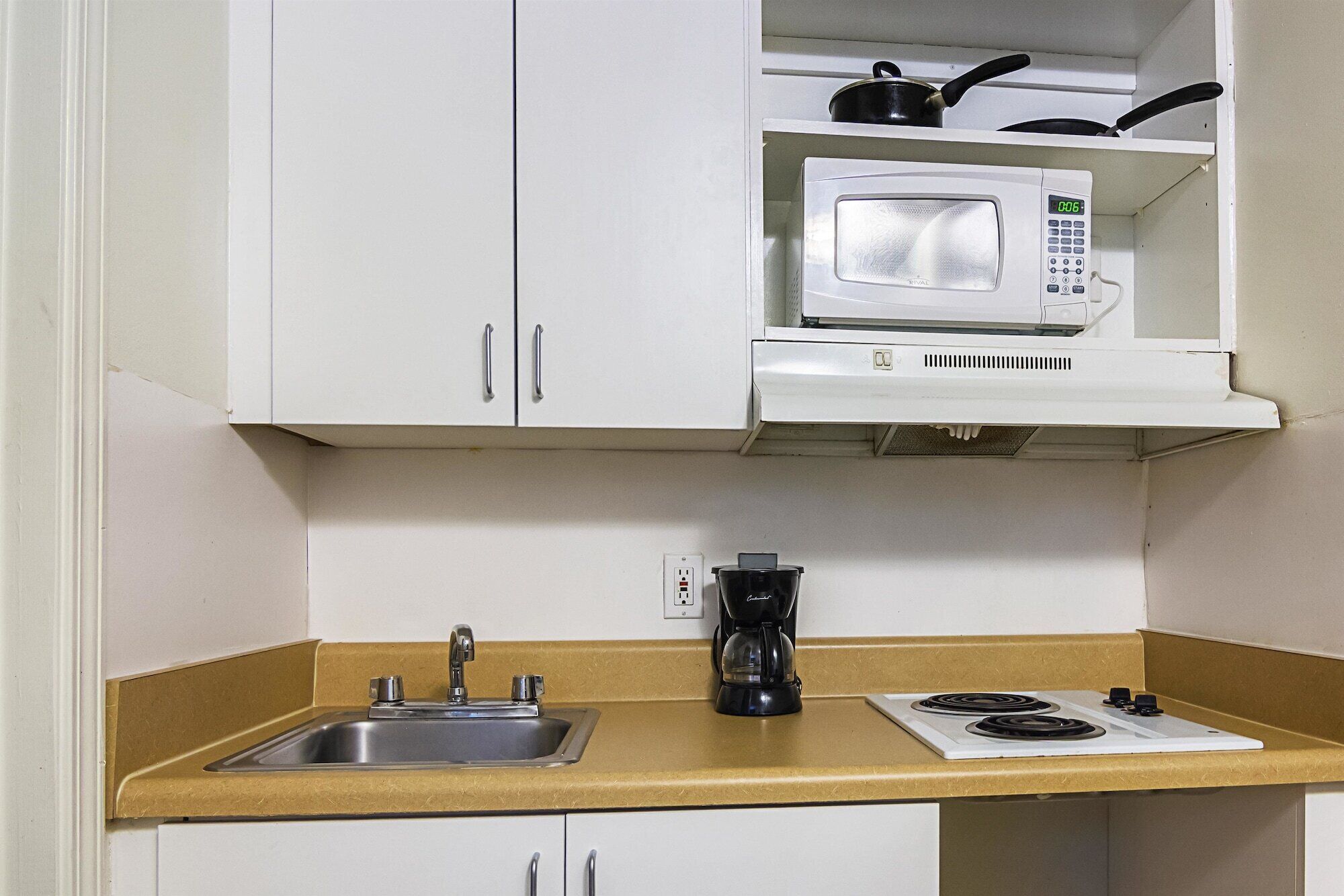 A compact kitchenette with a microwave, a coffee maker, and a stove.