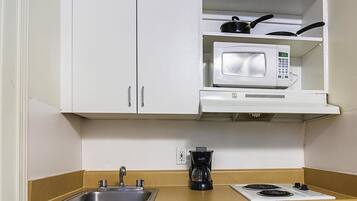 A compact kitchenette with a microwave, a coffee maker, and a stove.