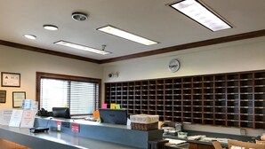A reception desk with a computer, a sign indicating no pet rooms, and a wall with a grid of storage boxes. - Motel 6 - Fayetteville, NC - Fort Liberty Area (Fayetteville)