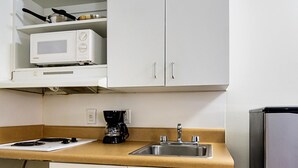 A kitchen with a microwave, stove, coffee maker, and a sink. - Motel 6 - Fayetteville, NC - Fort Liberty Area (Fayetteville)