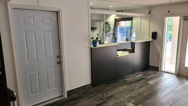 A hallway with a grey door, a reception desk, and a ceiling fan. - Motel 6 Richmond, VA - I-64 West (Richmond)