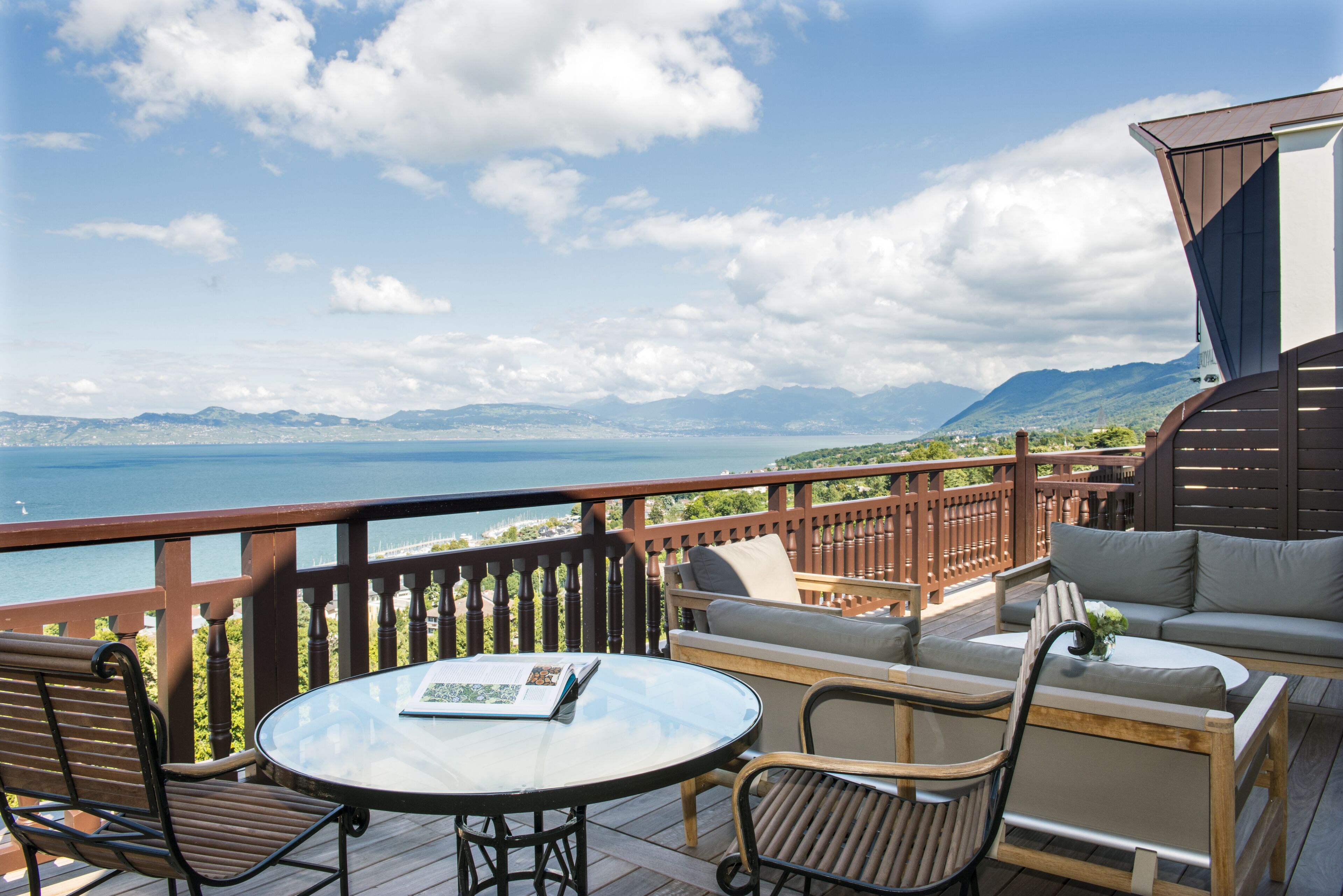 Une terrasse avec une table ronde et des chaises, un canapé et une vue sur la mer et les montagnes.