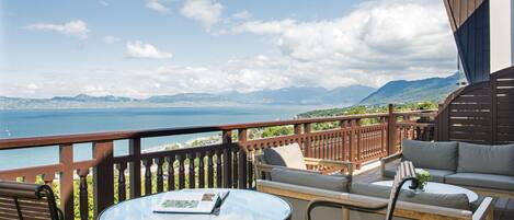 Une terrasse avec une table ronde et des chaises, un canapé et une vue sur la mer et les montagnes.
