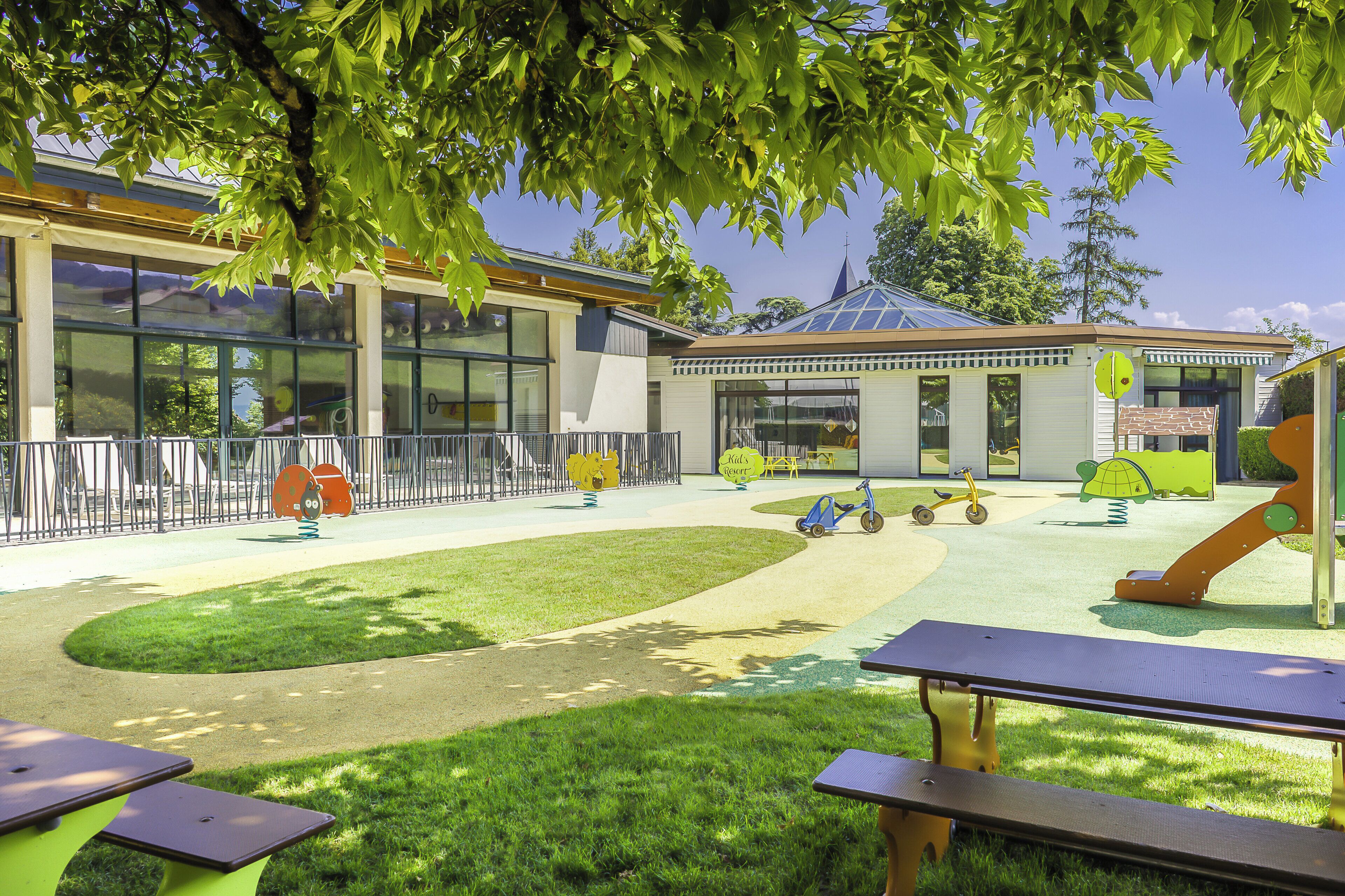 Un parque infantil con toboganes y columpios, una zona de estar cubierta y mesas de picnic.