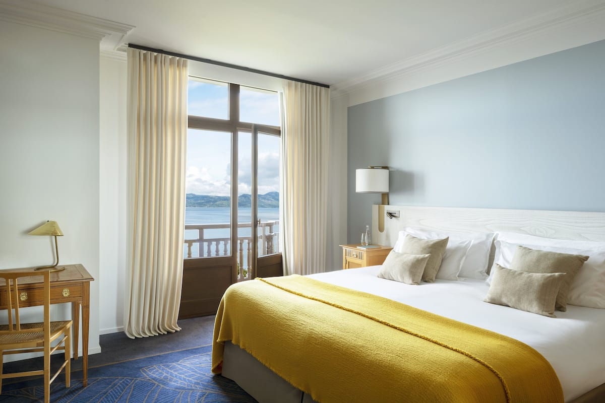 Een hotelkamer met een groot bed, een bureau, een lamp en uitzicht op het buiten.