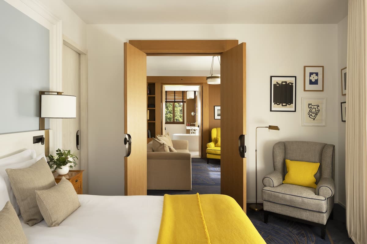 Een hotelkamer met een bed, een stoel, een bureau en uitzicht op buiten.