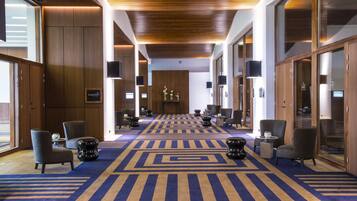 A hotel lobby with a patterned carpet, wooden paneling, and modern furniture.