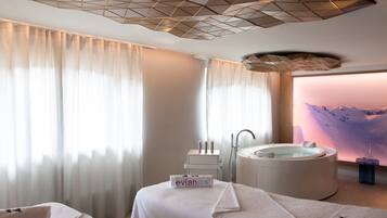 Une salle de spa équipée d’une table de massage, d’une baignoire et d’un fauteuil de massage fixé au mur.