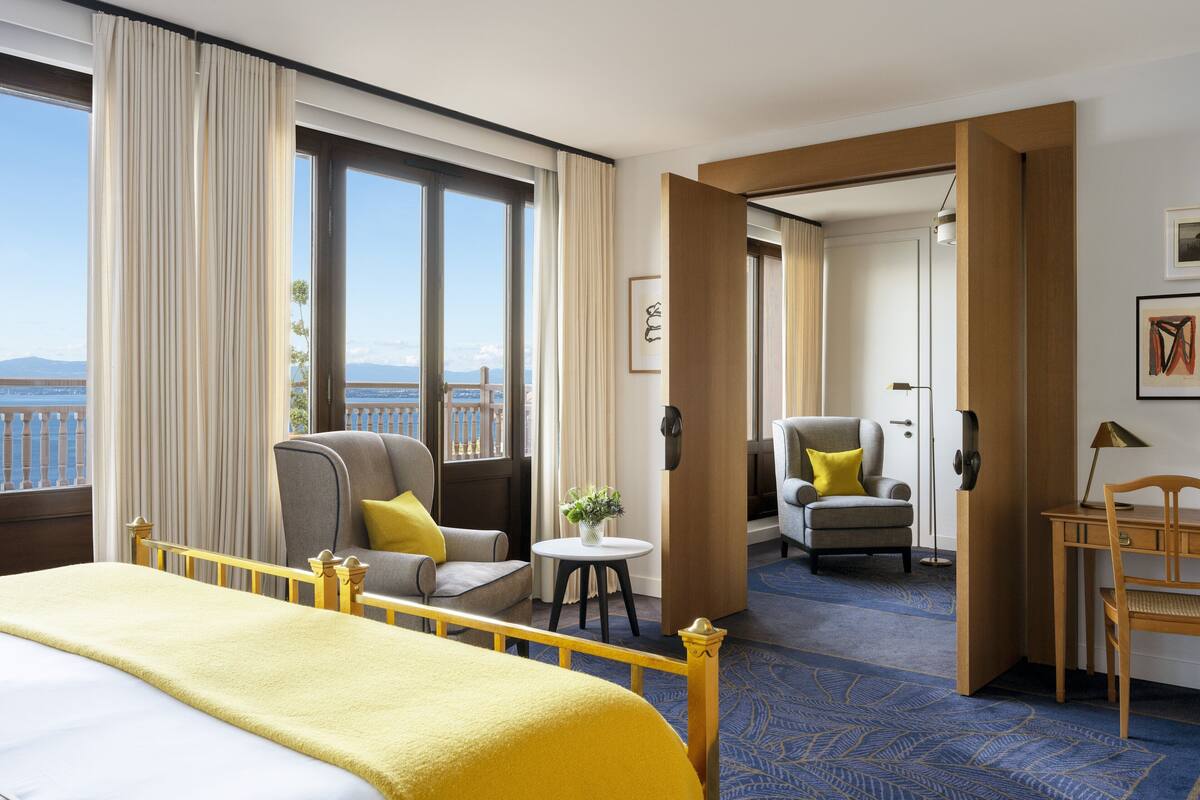Een hotelkamer met een groot bed, een bureau, een stoel en uitzicht op de zee.