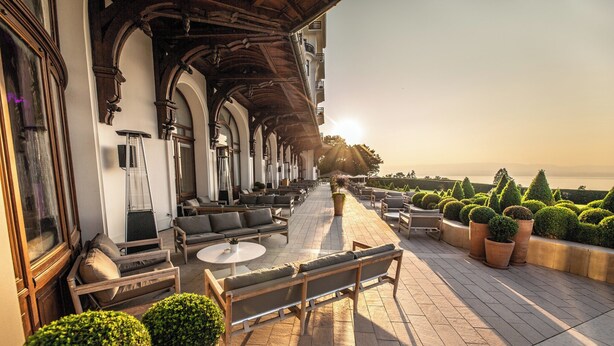 Une terrasse avec des places assises à l’extérieur, une vue sur la mer et un bâtiment doté de fenêtres en arc de cercle et d’un plafond en bois.