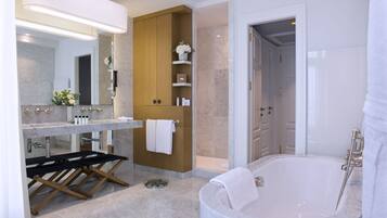 Un baño moderno con lavamanos de mármol, bañera independiente y estanterías de madera.