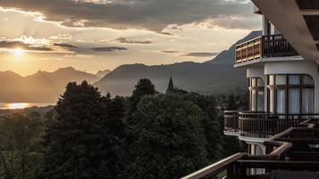 Un hotel con balcón y vistas a un paisaje montañoso al atardecer.