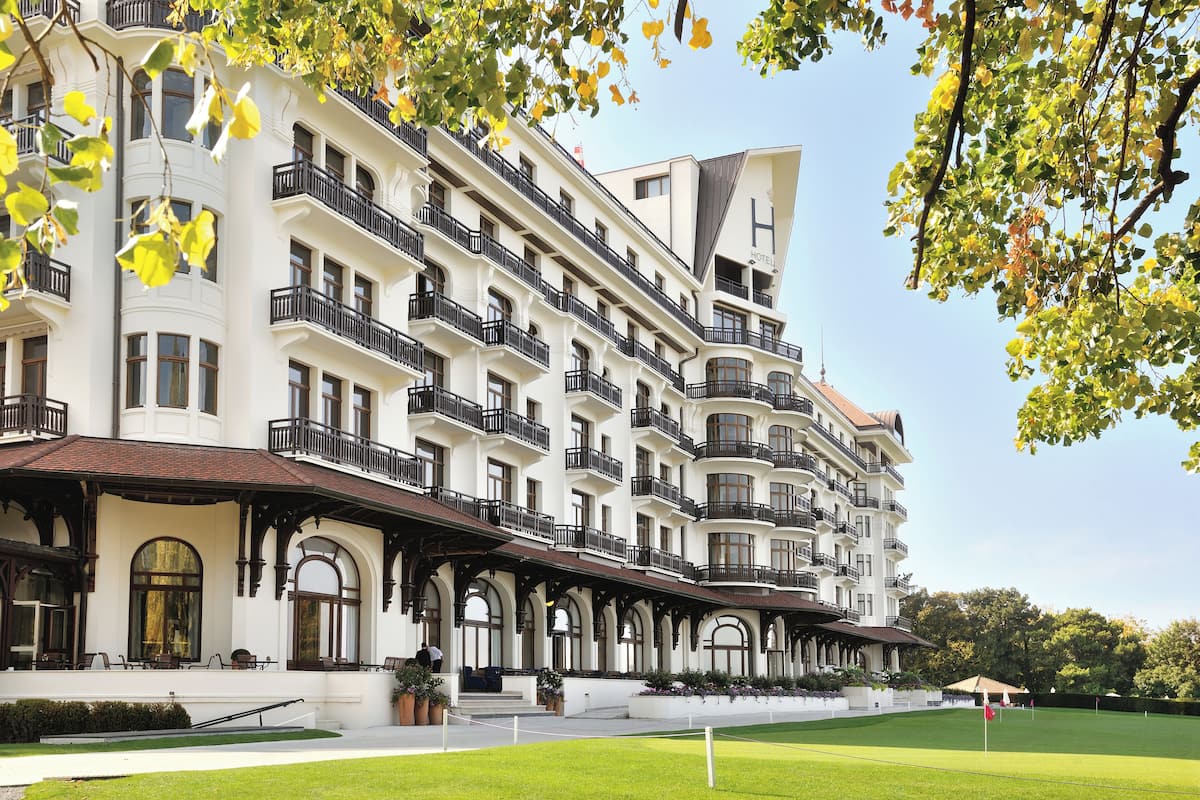 Een hotel met meerdere verdiepingen, balkons, een verzorgd gazon en een heldere lucht.