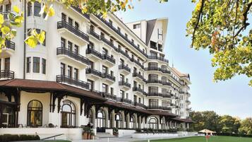 Un hotel de varios pisos con balcones, un césped cuidado y un cielo despejado.
