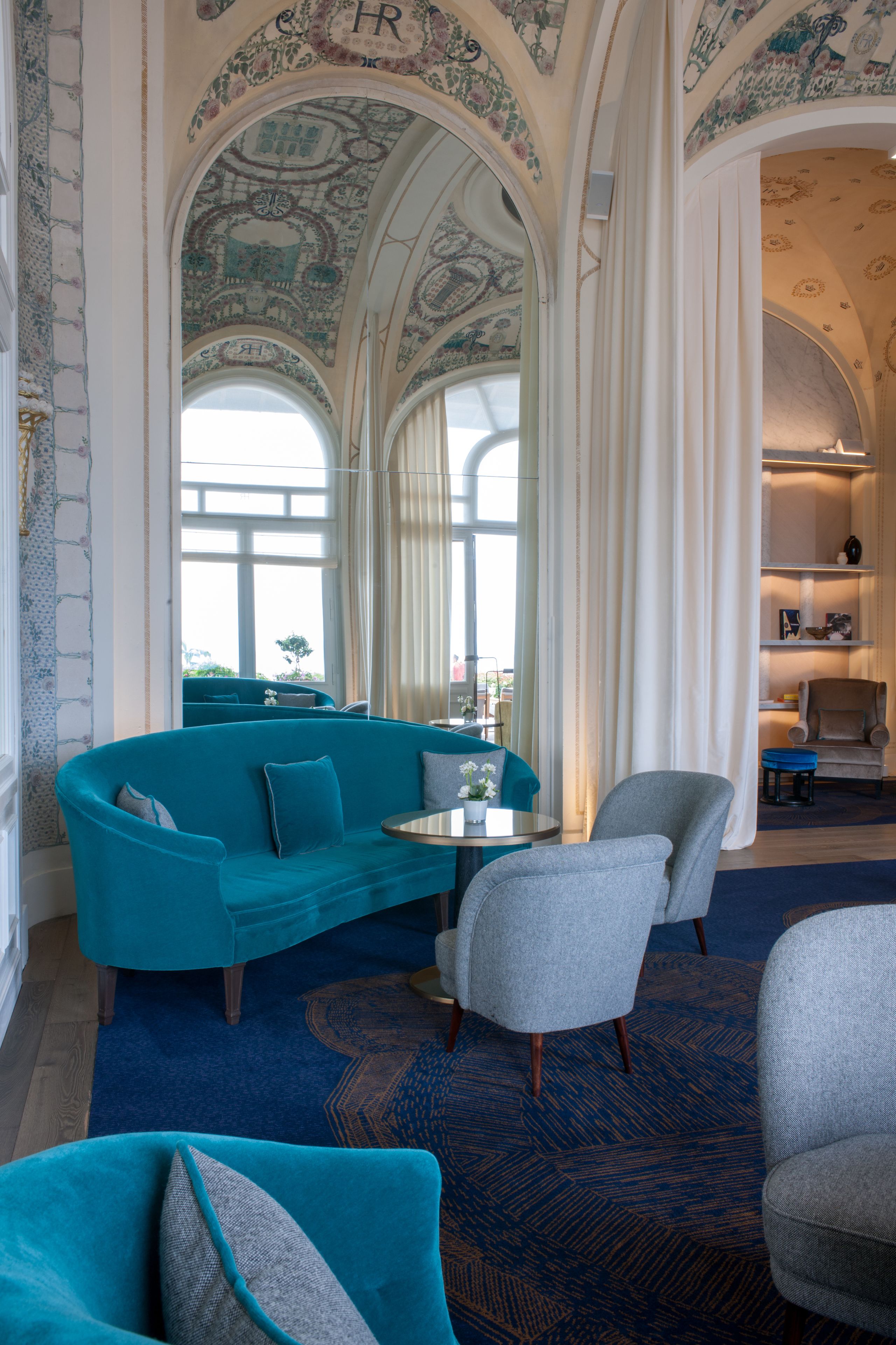 A room with a teal sofa, a grey armchair, and a small round table.