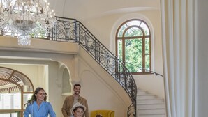 Un interior espacioso con una escalera, un candelabro y un suelo con diseño.