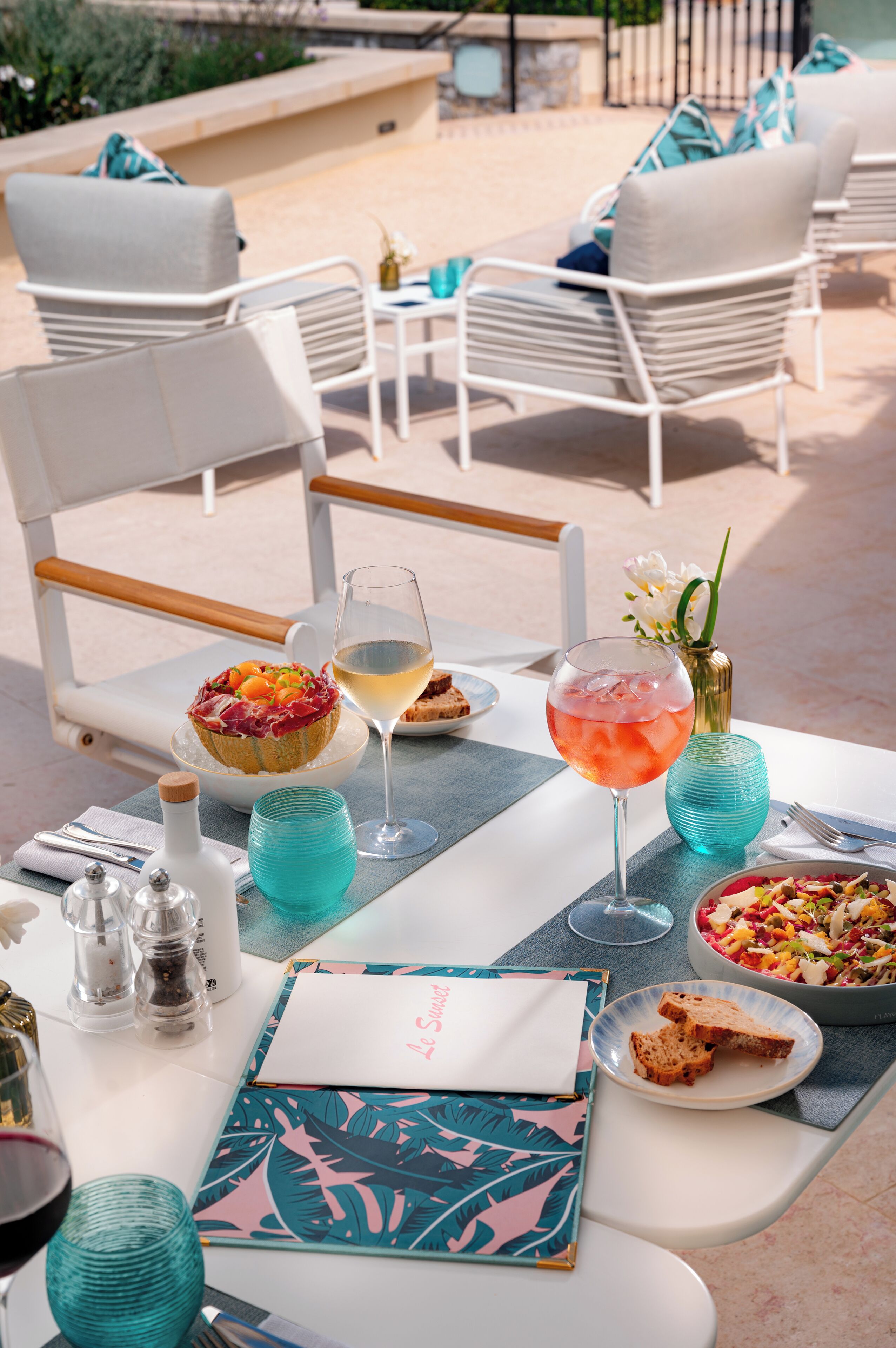 A dining table set with a meal, drinks, and a decorative vase.