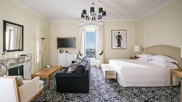 A hotel room with a sofa, a bed, a TV, a fireplace, and a balcony view.