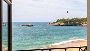 A coastal view with a lighthouse, beach, and rocky outcrops.