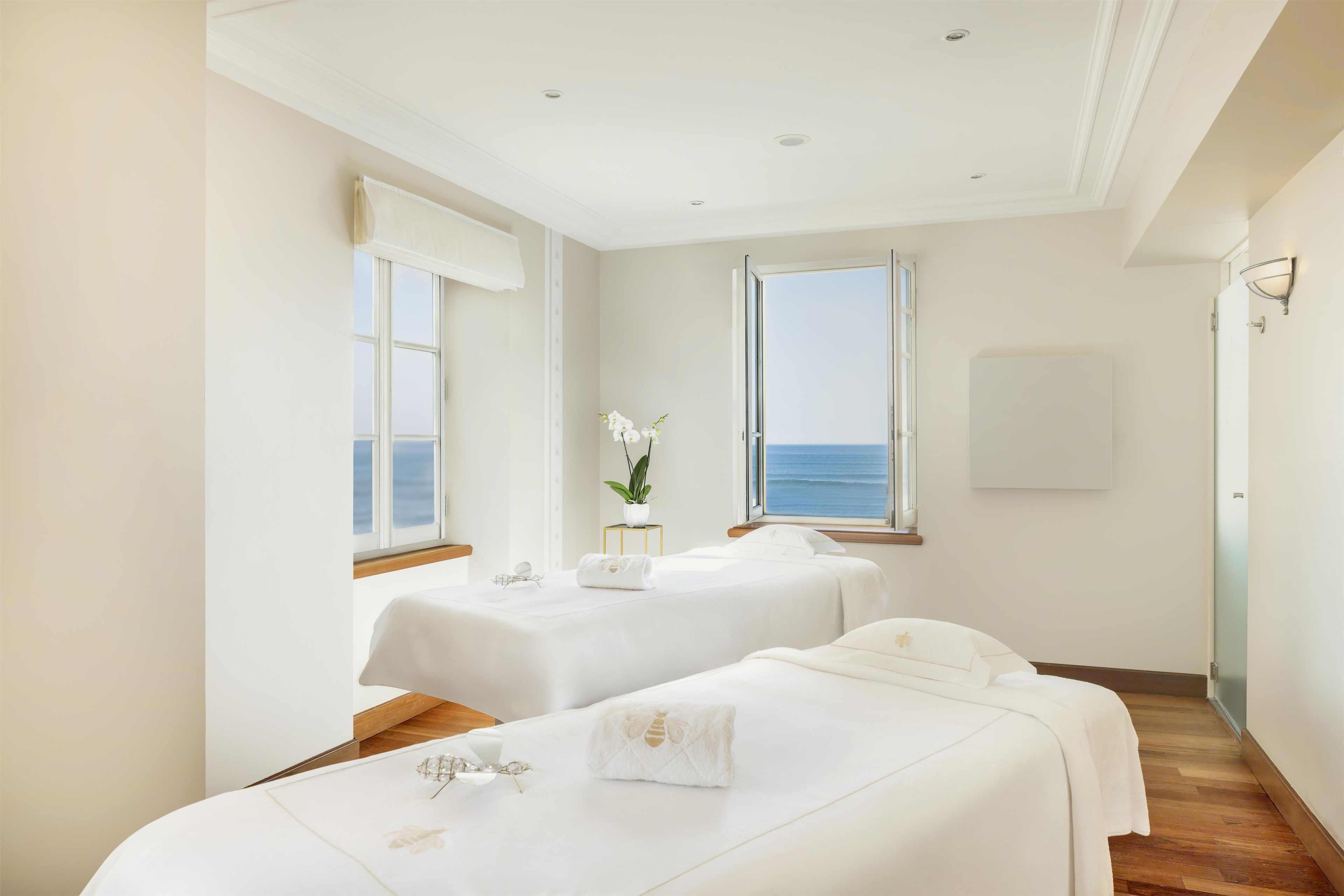 Una camera d'albergo con due letti, vista mare e una pianta in vaso.