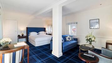 Ein Hotelzimmer mit einem Bett, einem Sofa, einem kleinen Tisch, einem Sessel und einem Schreibtisch mit Blumen in einer Vase.