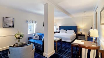 Una habitación de hotel con cama, sofá, sillón, mesita y lámpara.