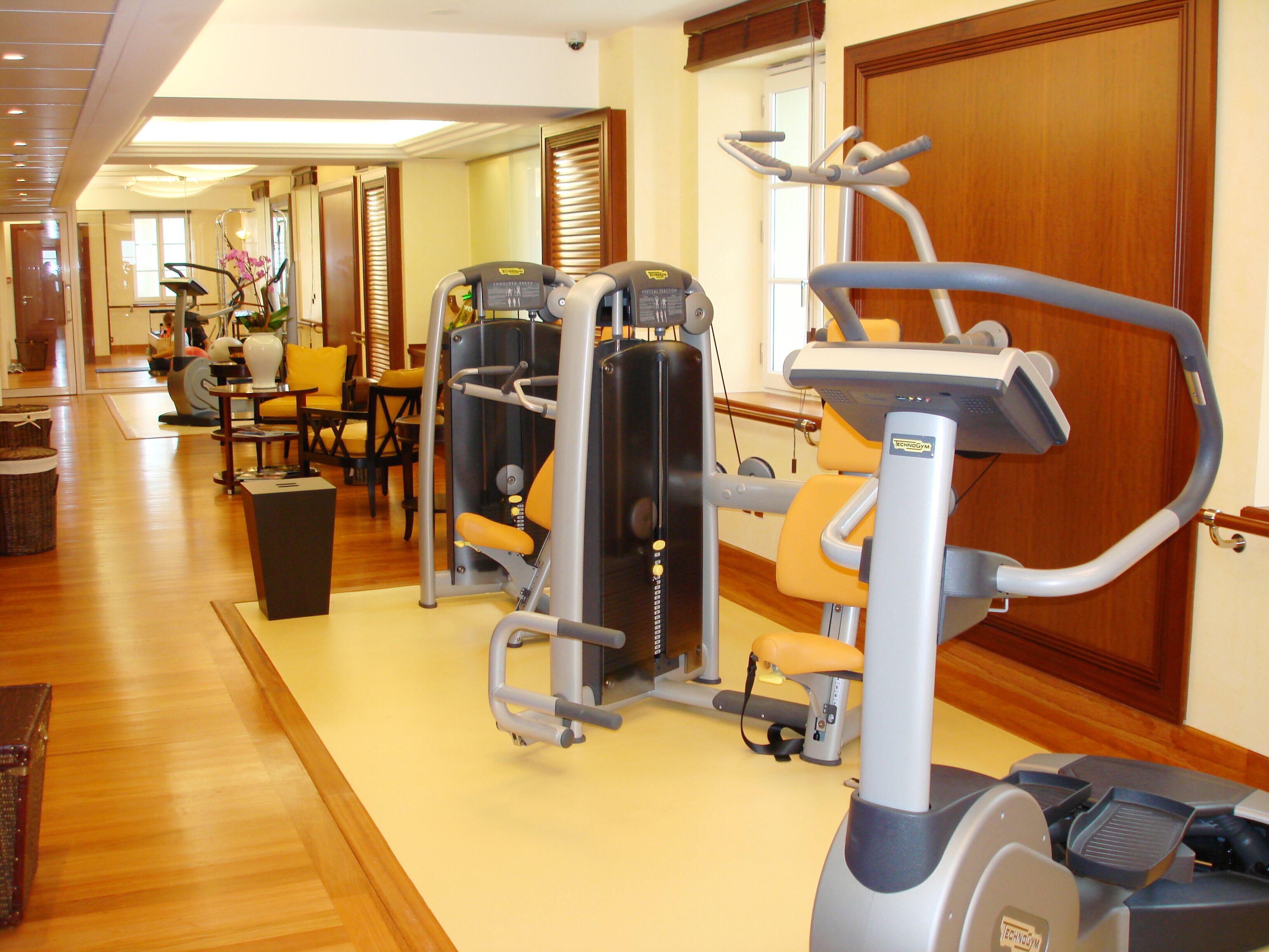 Een hotel fitnessruimte met cardioapparatuur, krachttrainingsapparatuur en een yogamatgedeelte.