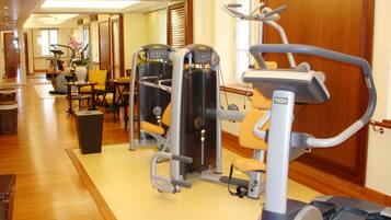 Un gimnasio hotelero con máquinas de cardio, equipo de entrenamiento de pesas y una zona de colchonetas de yoga.
