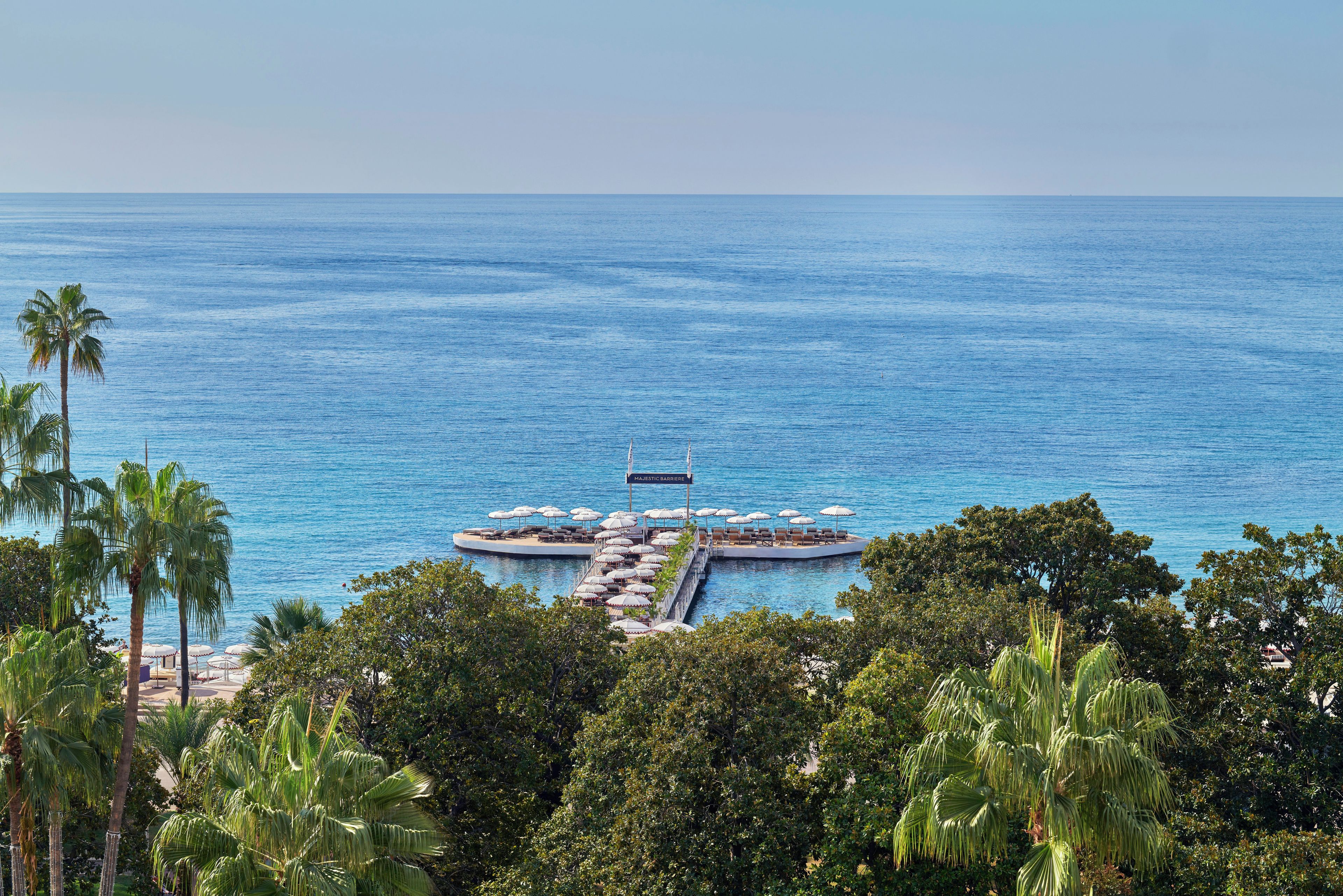 A waterfront property with a pier extending into the sea, featuring outdoor seating and a sign reading 'MAJESTIC BAY.'