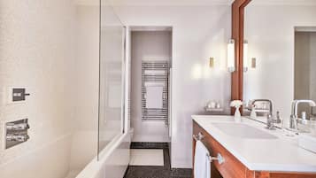 A modern bathroom with a glass-enclosed shower, a large vanity with a mirror, and a towel rack.