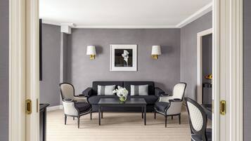 Una sala moderna con un sofá gris oscuro, dos sillones, una mesa de centro y una obra de arte enmarcada en la pared.