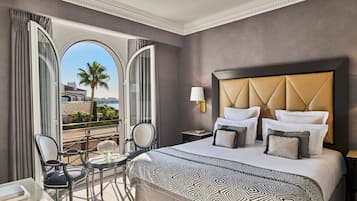 Une chambre d’hôtel dotée d’un grand lit, d’un balcon avec vue et d’un coin salon avec une table et des chaises.