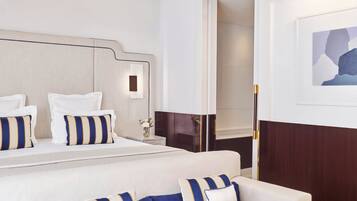 Habitación de hotel con una cama grande, un sofá, una mesita de noche y un espejo.