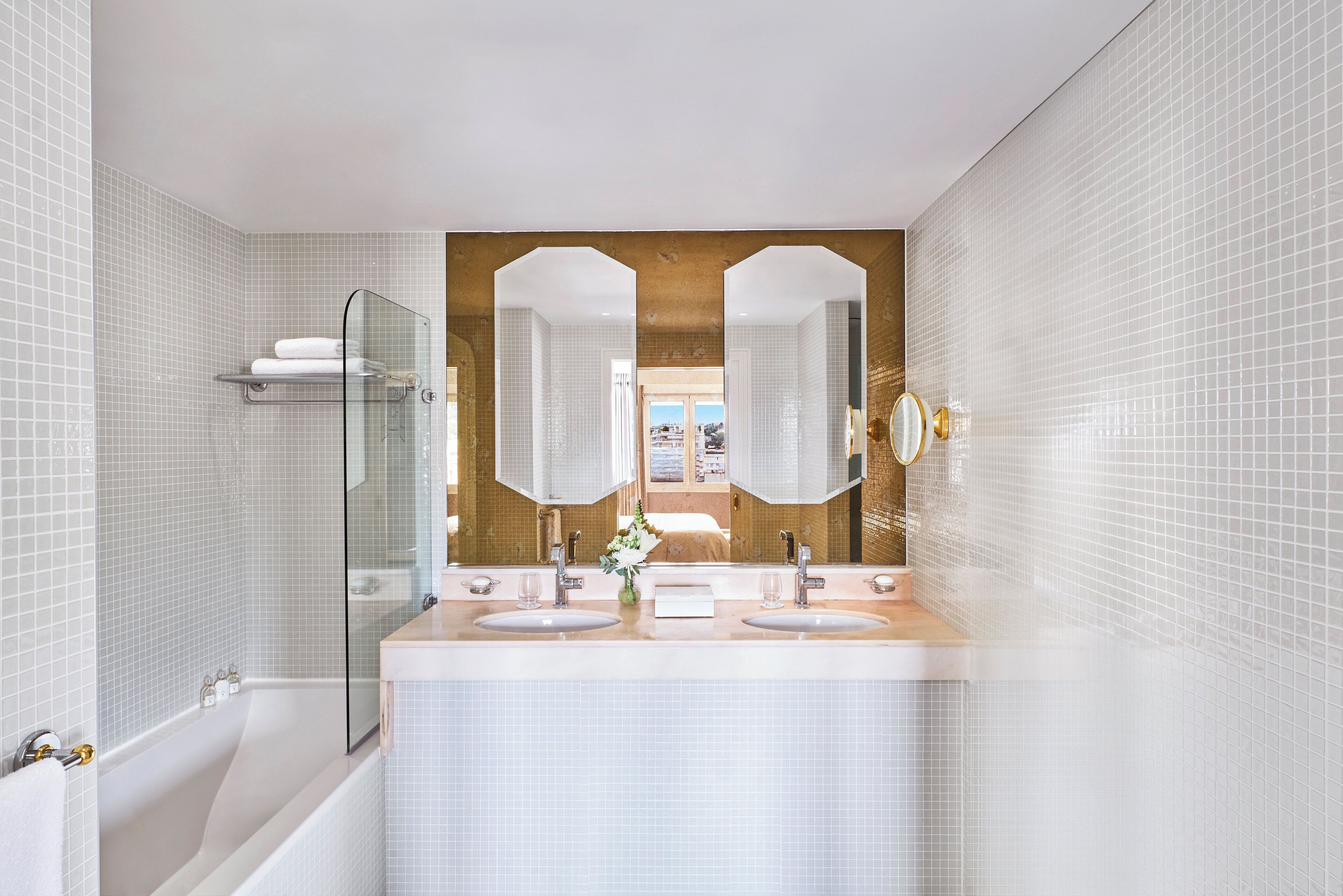 A modern bathroom with a large mirror, two sinks, and a glass shower enclosure.
