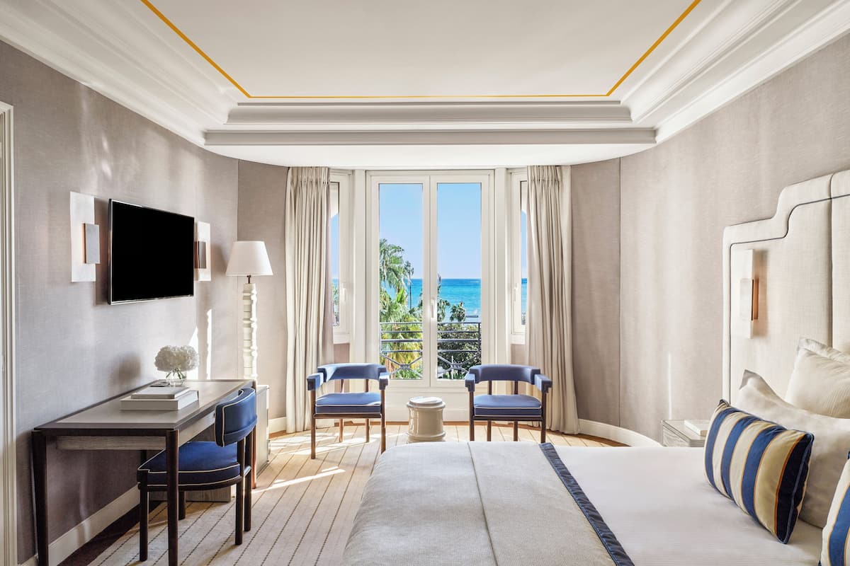 Una habitación de hotel con una cama grande, dos sillas, un escritorio y un televisor.
